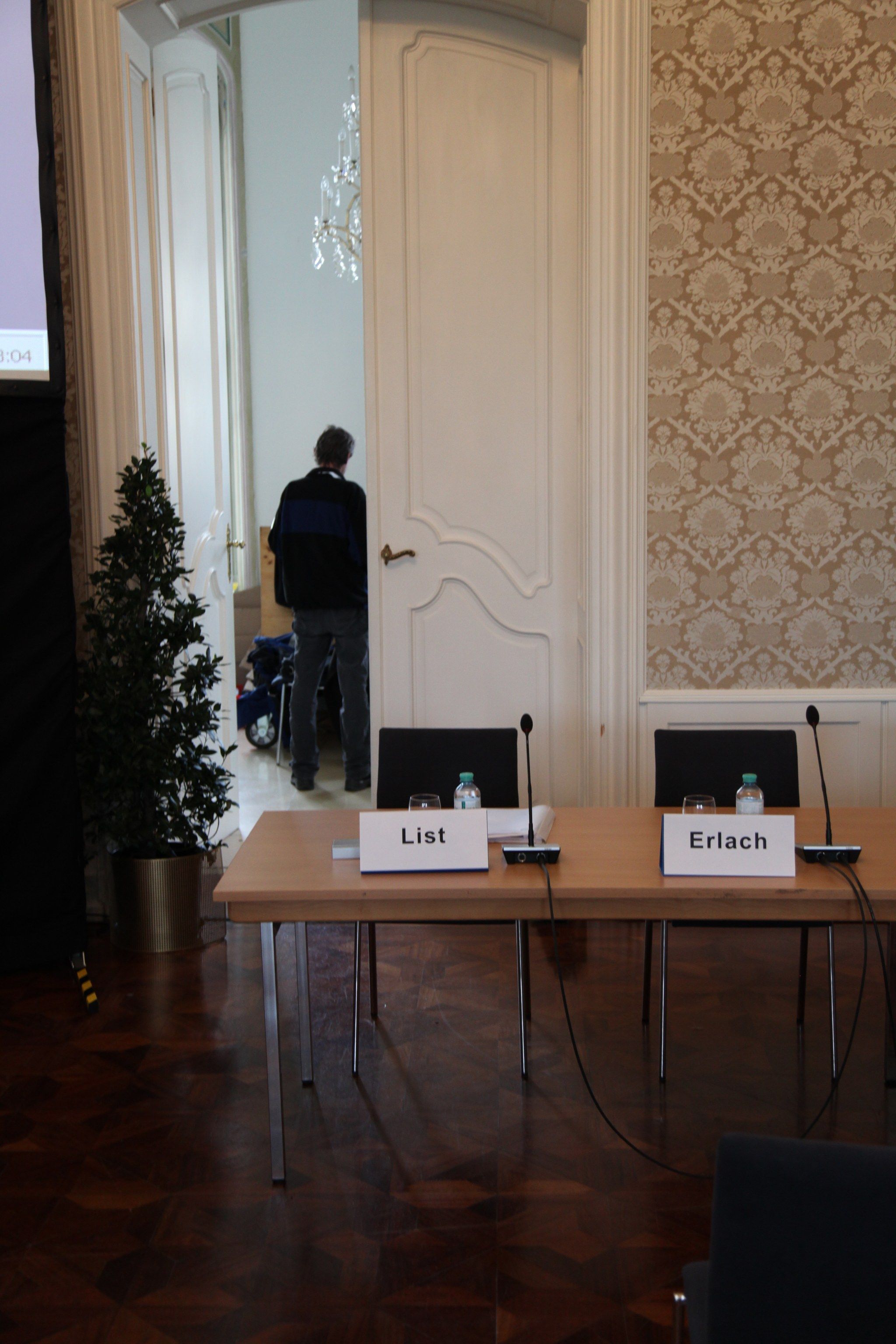 Podiumstisch mit Mikrofonen und den Namensschildern List und Erlach.
